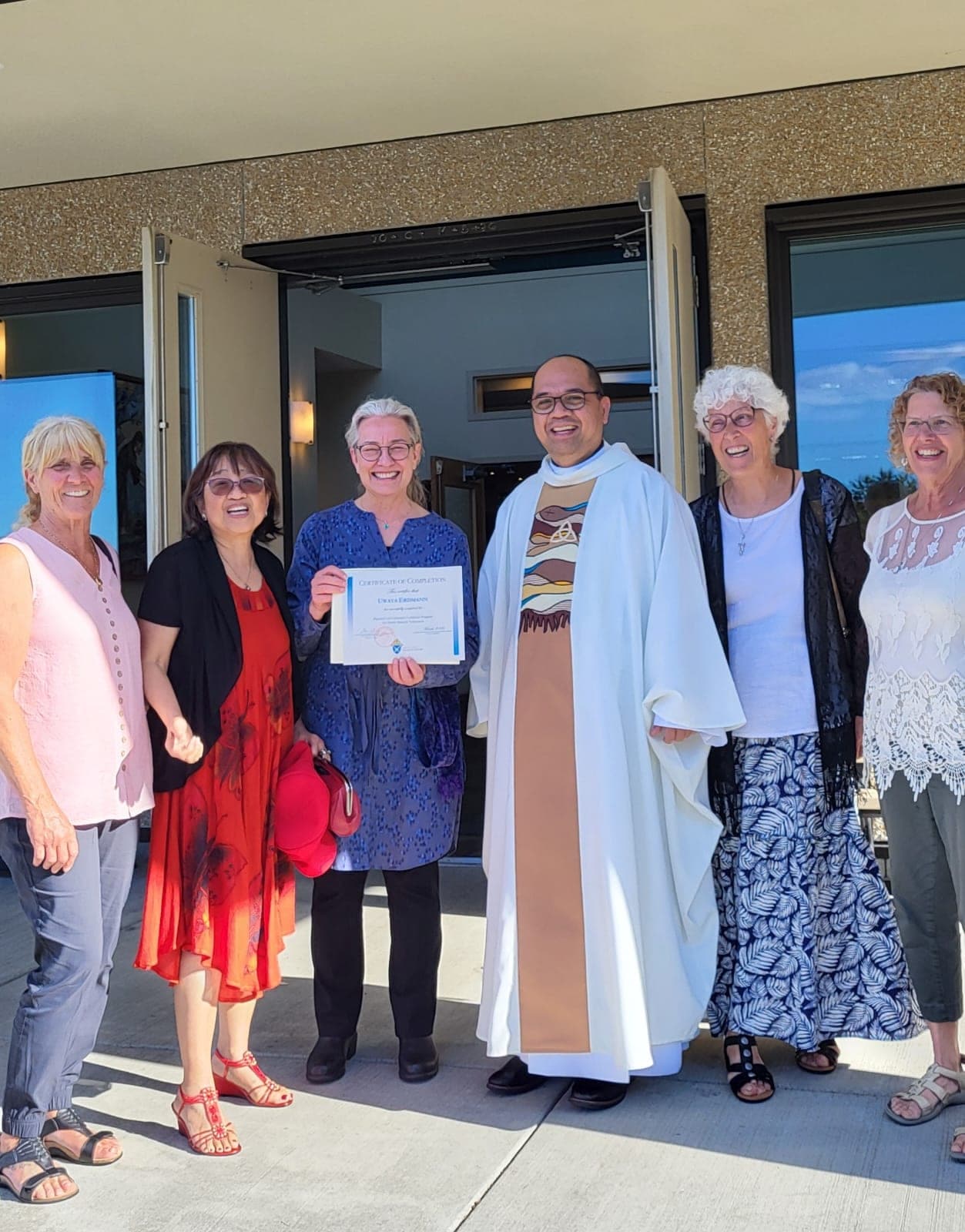 Parishioners and the priest smiling together outside the church after Mass