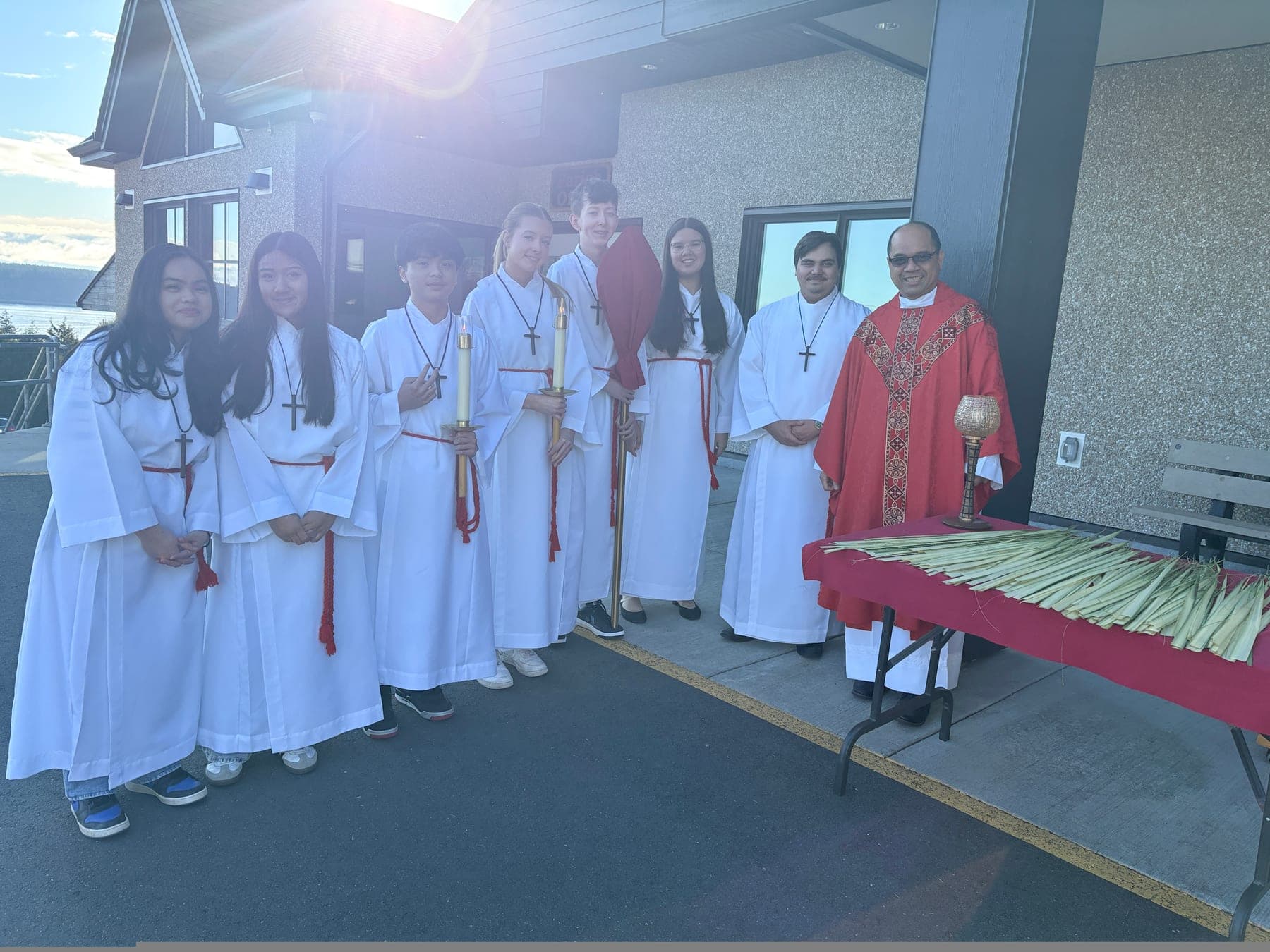 Altar servers and clergy gathered outside the church with palms on Palm Sunday