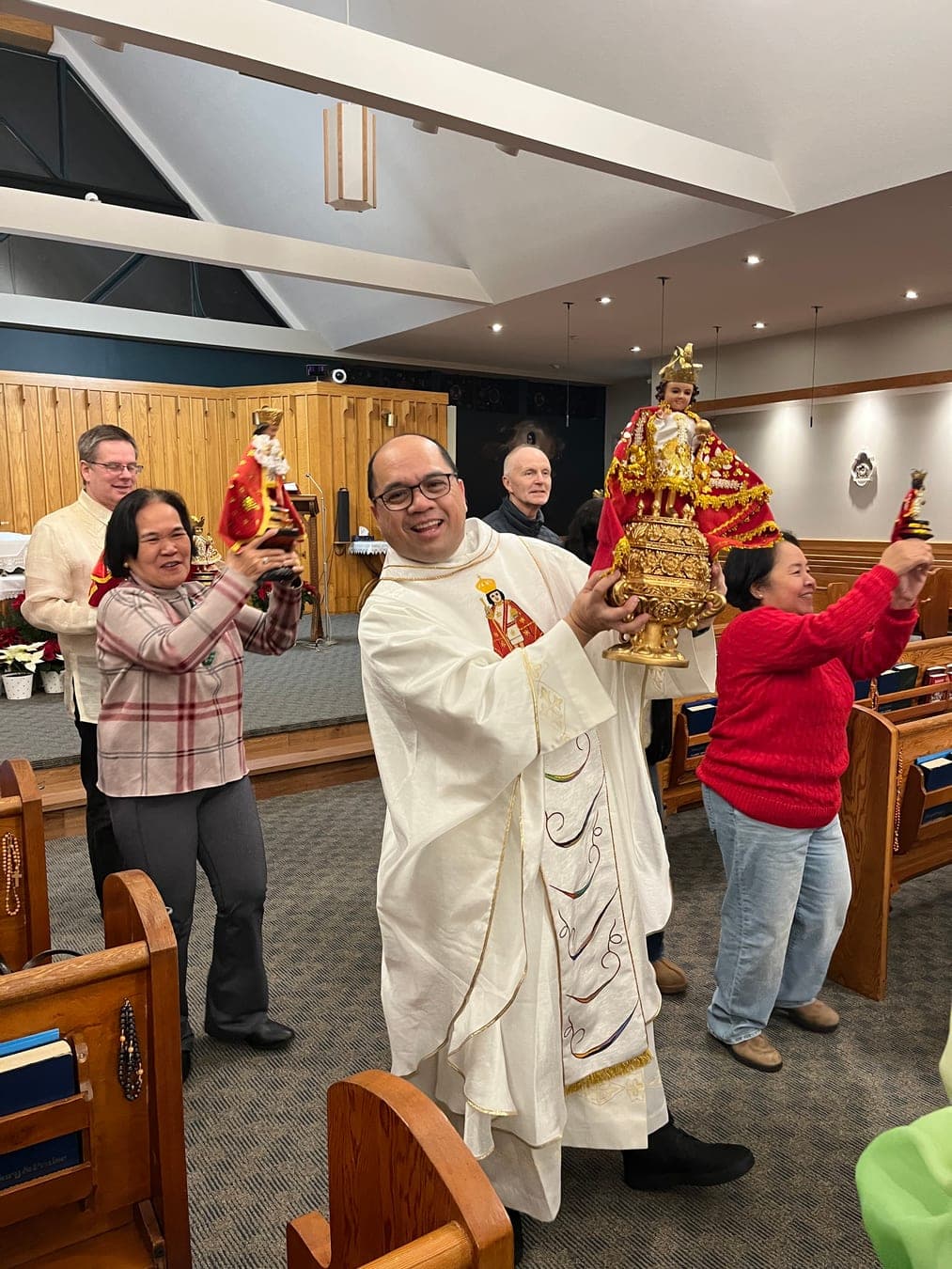 The priest and parishioners joyfully carrying statues of the Holy Child through the church