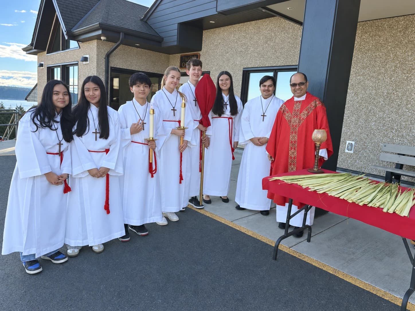 Altar servers and clergy gathered outside the church with palms on Palm Sunday