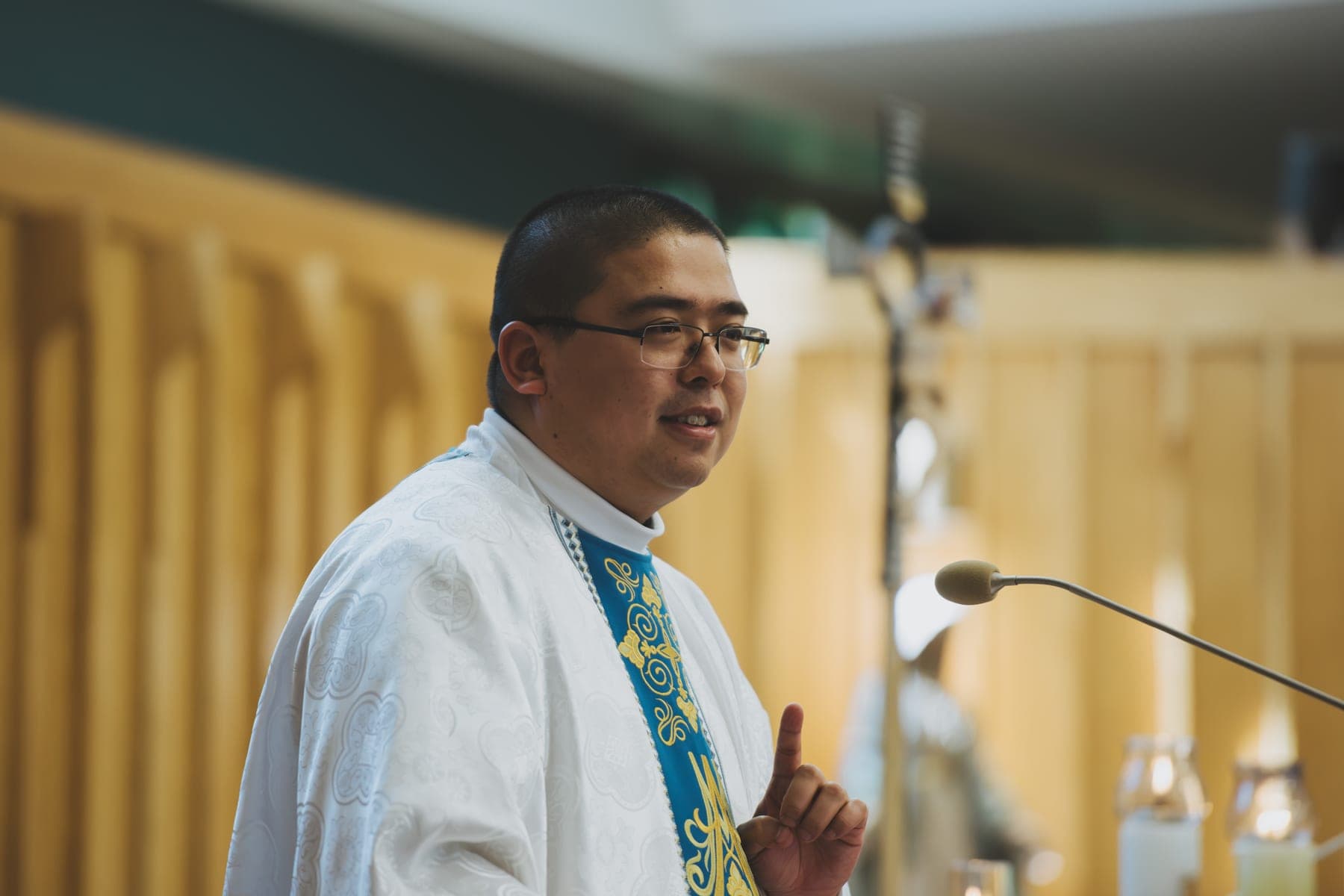 The priest preaching the homily at the microphone during Mass
