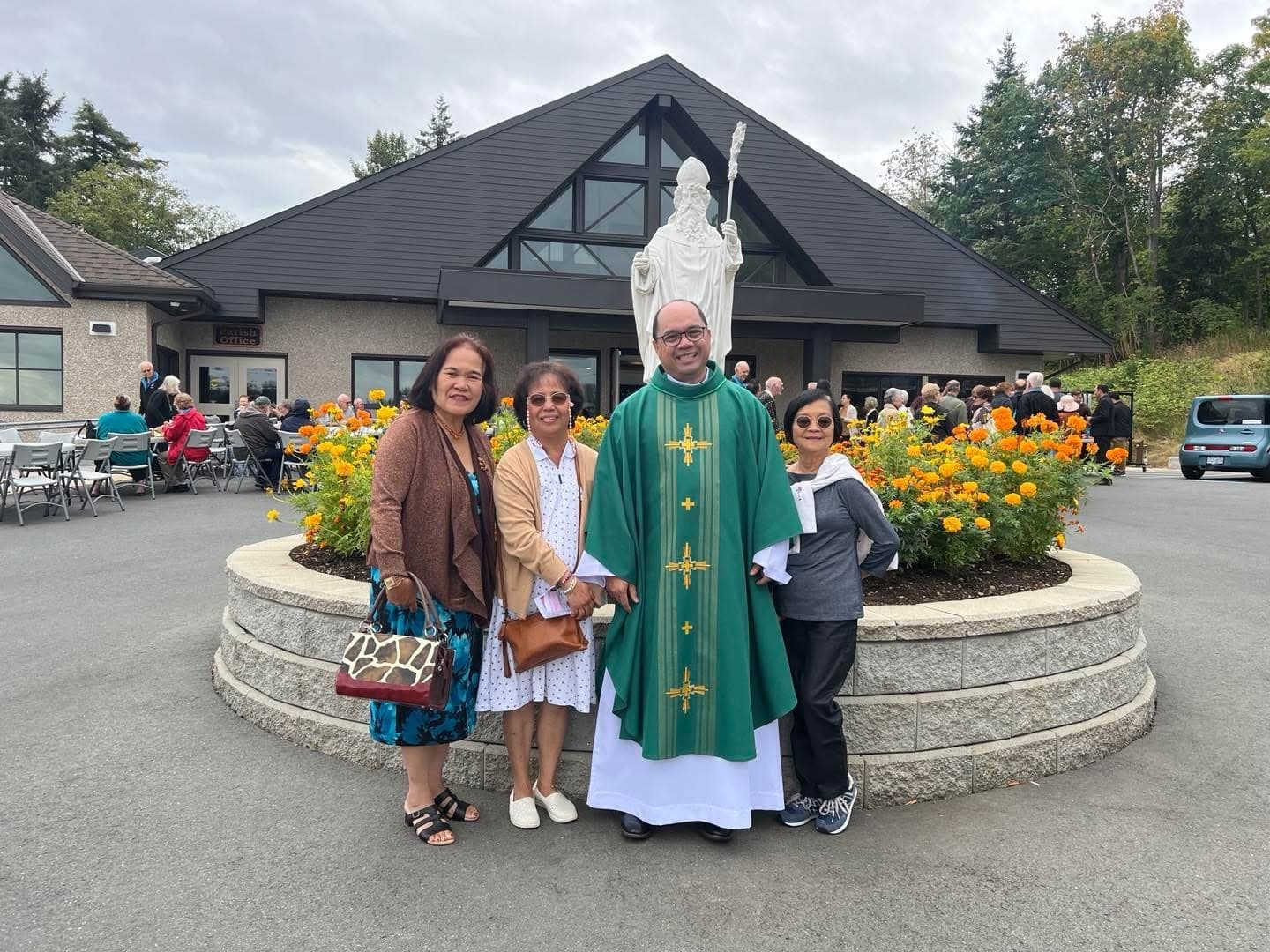 Parishioners and the priest gathered in the courtyard during a community barbecue