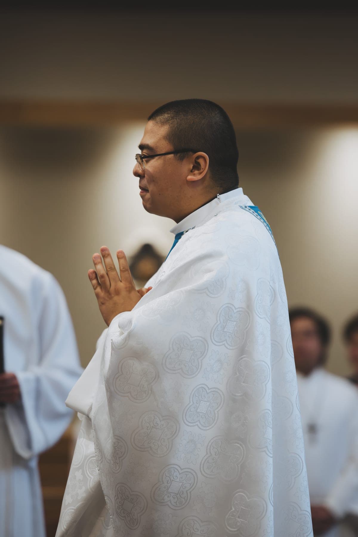 The priest standing with hands joined in prayer during Mass