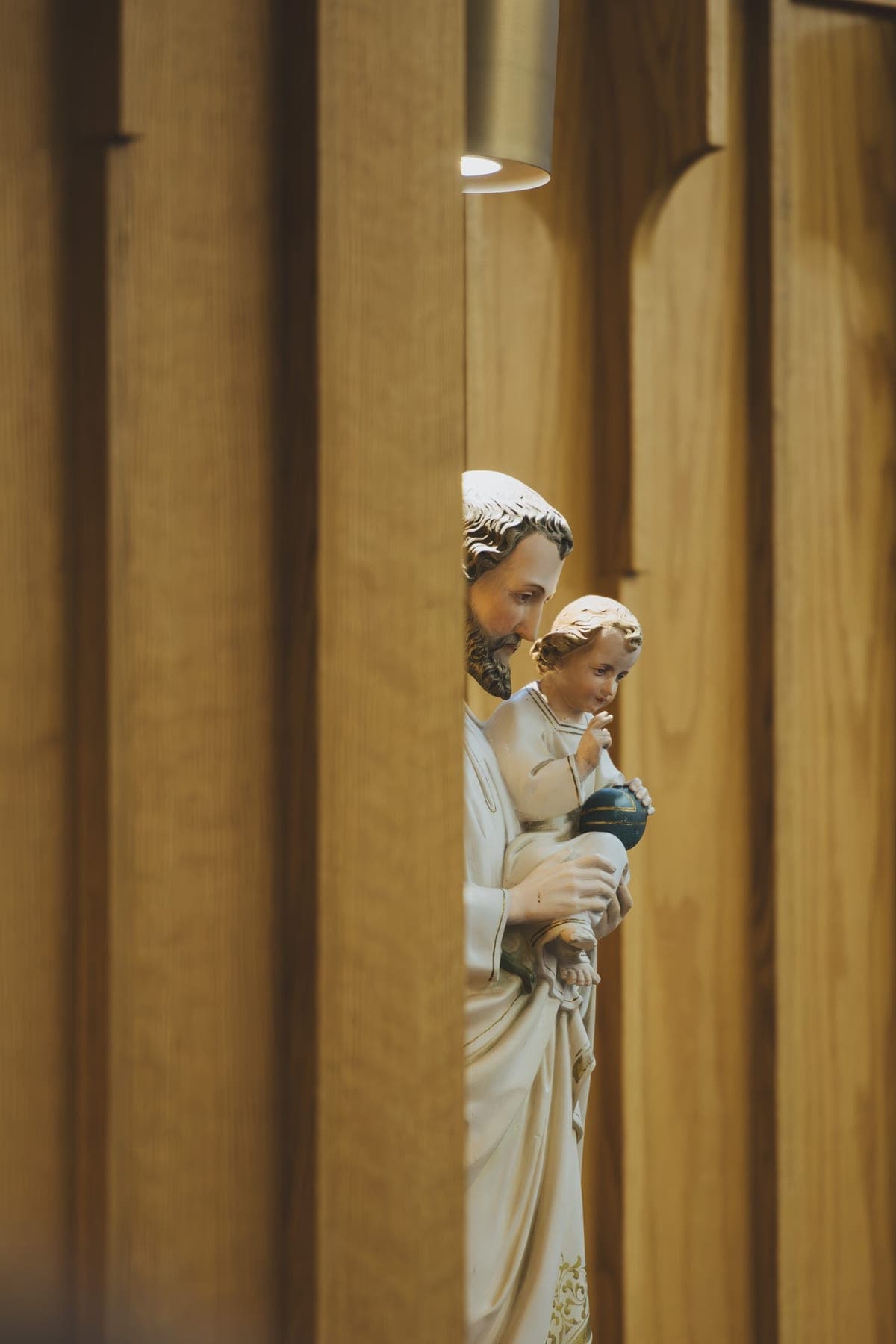 Statue of St. Joseph holding the child Jesus, framed between the cedar panels of the church wall